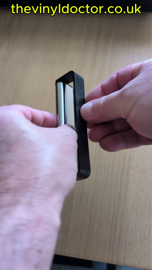 Rotating the plastic handle back and forth, which scrapes the dust from the bristles.