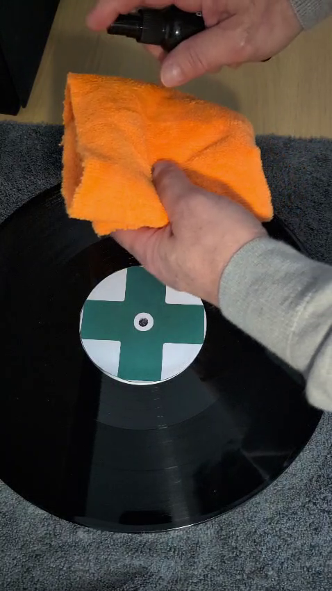 Two microfibre cloths and a small spray bottle prepared for gentle wet cleaning of vinyl records.